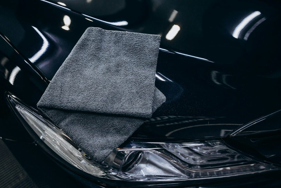 Microvezeldoek op de glanzende motorkap van een zwarte auto