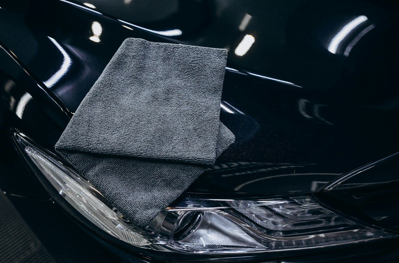 Microvezeldoek op de glanzende motorkap van een zwarte auto